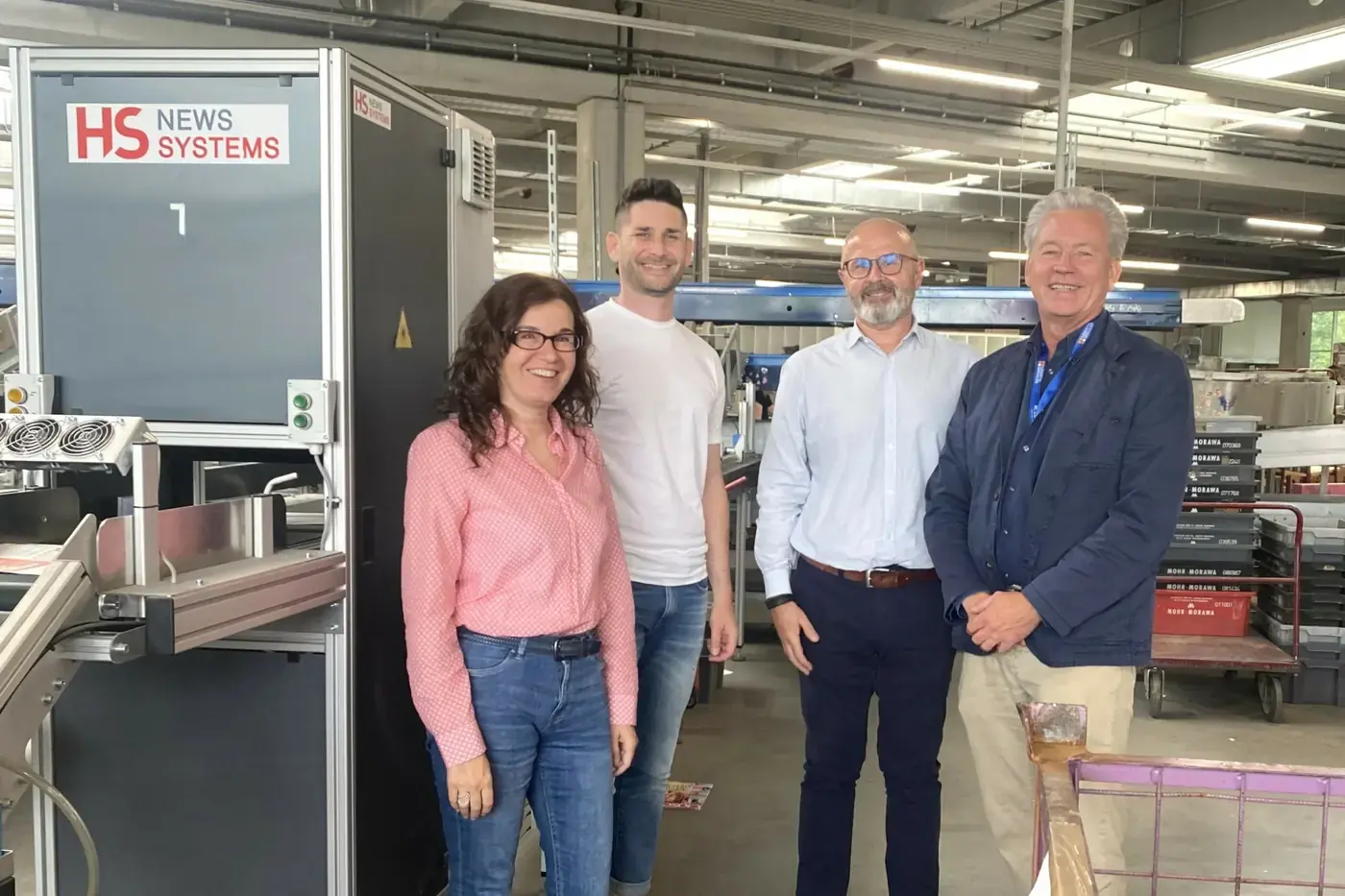 HS News Systems team members together with customers in front of an HS line